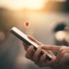 Woman hand using smart phone with navigator location point at street background. Technology interenet and travel adventure concept.