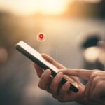 Woman hand using smart phone with navigator location point at street background. Technology interenet and travel adventure concept.