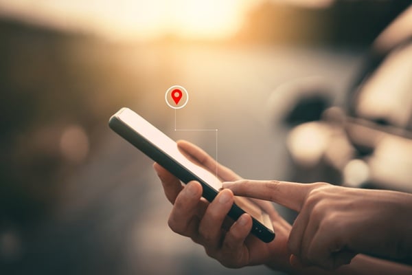 Woman hand using smart phone with navigator location point at street background. Technology interenet and travel adventure concept.