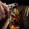 Pouring strong alcohol drink into the glasses which are on the w