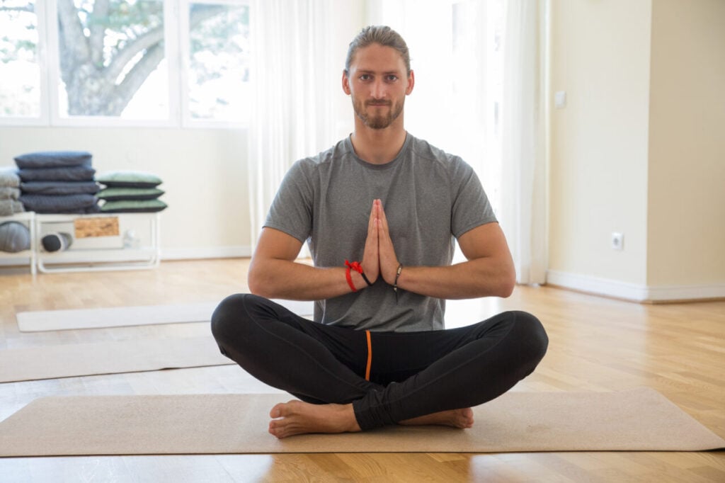 Serious man keeping hands together at yoga class