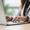 Closeup businesswoman hands typing on laptop keyboard answering email or searching information