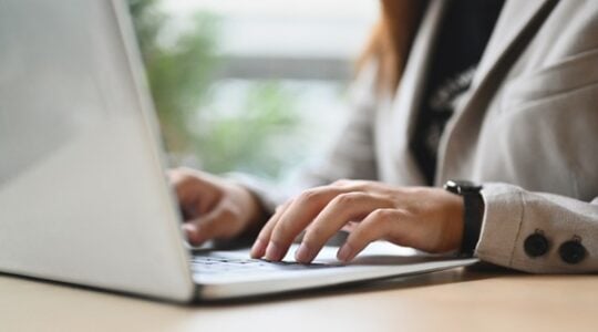 Closeup businesswoman hands typing on laptop keyboard answering email or searching information